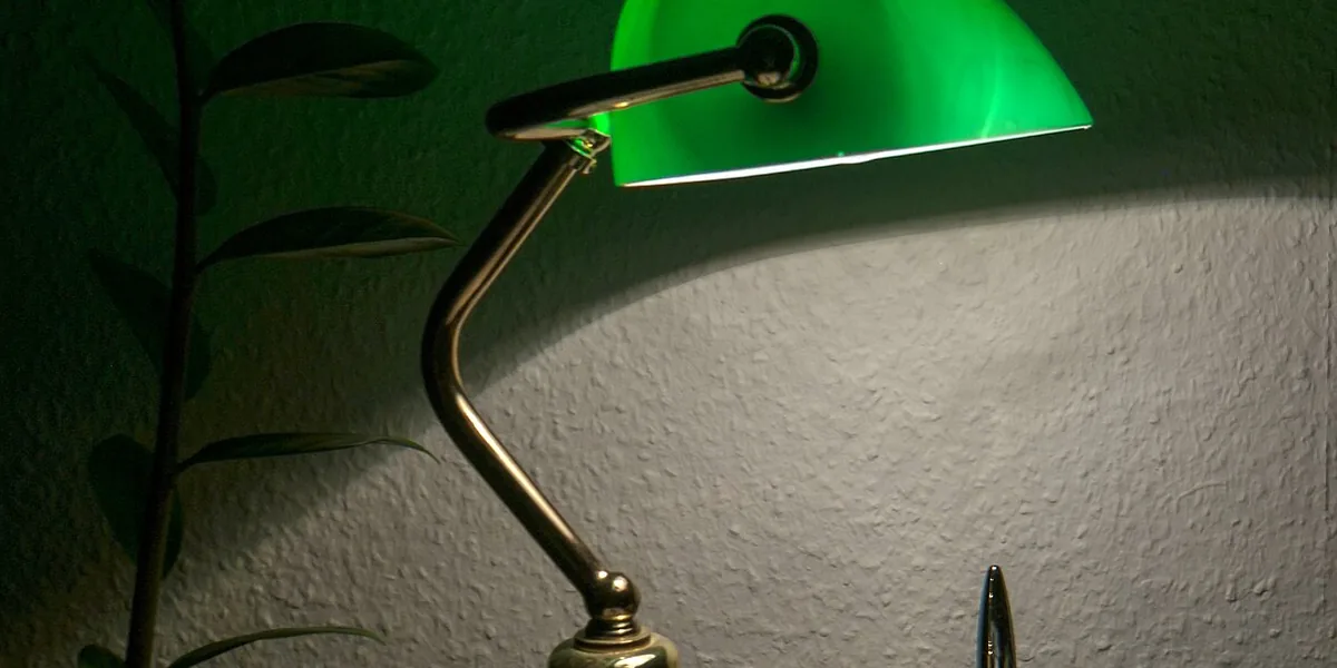 Grüne Schreibtischlampe an der Wand neben einer Pflanze