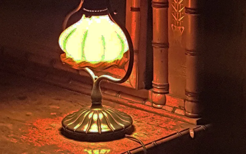 Kleine Lampe auf einem dunklen Tisch vor einem Stuhl